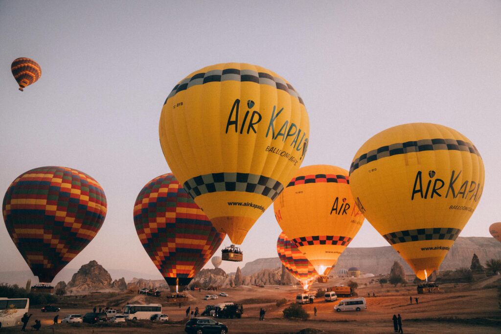 Hot air balloons flying over Cappadocia at sunrise in Göreme valleys during 2026 flight season.