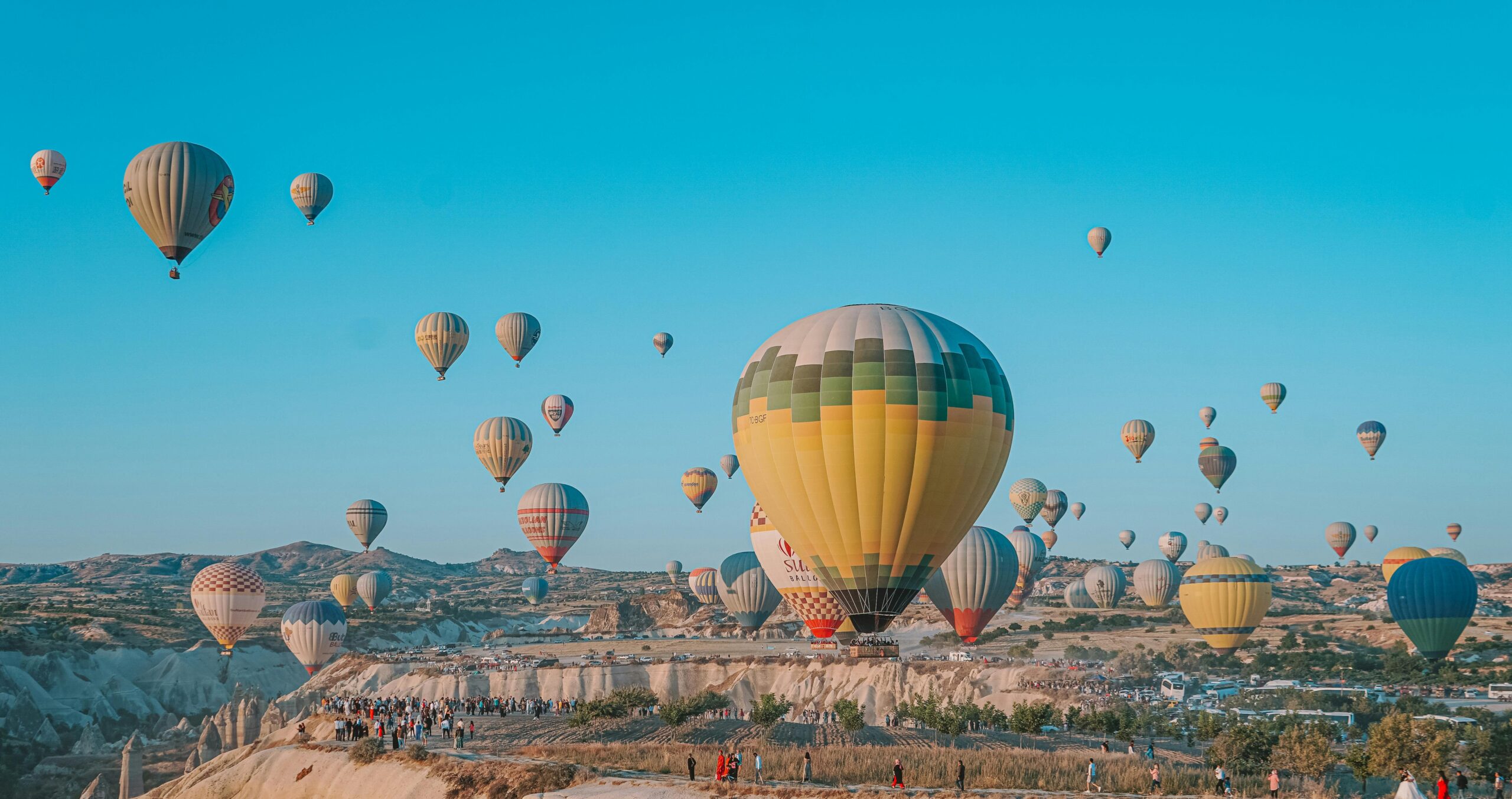 Multiple hot air balloons flying in Cappadocia sky during early morning light over valleys